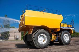 heavy yellow irrigating machine watering industrial area at sunny cloudless day photo