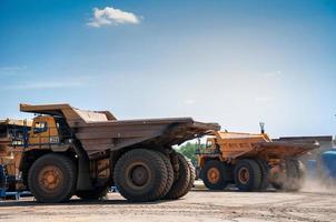 Quarry yellow dump truck drives alone industrial area at sunny day photo