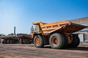 Quarry yellow dump truck drives alone industrial area at sunny day photo