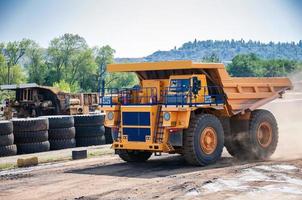 Quarry yellow dump truck drives alone industrial area at sunny day photo