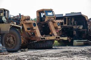 remains of old quarry trucks and machinery on junk yard at sunny day photo