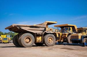 heavy yellow open cast mine dump trucks at repair station at sunny cloudless day photo