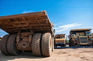 heavy yellow open cast mine dump trucks at repair station at sunny cloudless day photo