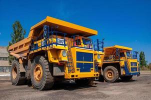 heavy yellow open cast mine dump trucks at repair station at sunny cloudless day photo