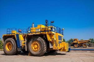 Heavy yellow quarry tractor at repair station at sunny cloudless day photo