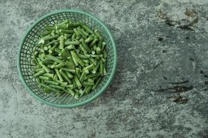 largo frijol piezas en un verde el plastico envase en un gris antecedentes foto