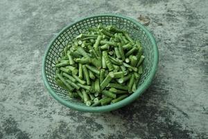 long bean pieces in a green plastic container photo