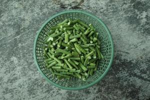 long bean pieces in a green plastic container photo
