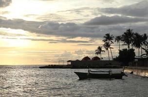 Silhouette of a fisherman's boat and a coconut tree on the beach with a sunset background photo