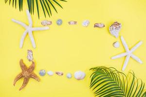 Starfish, shells in form of frame with palm tree on yellow background. Vacation, travel concept. Copy space photo