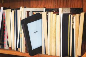 An e book reader in the midst of classic books photo