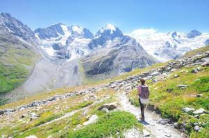 A woman alone walks on high mountain trail photo