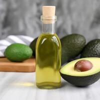 A bottle of olive oil with avocado on the table behind it photo