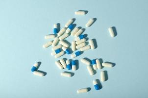 Randomly scattered pills. White and blue pills on blue background. photo