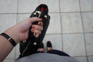 A woman is holding a black purse with a gold buckle. photo