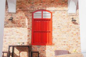 A red window with the word  on it  on the side of a brick wall. photo