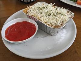 Cedar Cheese and mozzarella on the roasted beef lasagna with chili sauce. The photo is suitable to use for food background, poster and food content media.