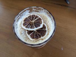 Arabica coffee ice with dried lemon slice with cream foaming. The photo is suitable to use for coffee shop background, menu poster and coffee content media.