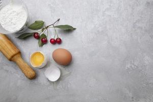 Ingredients for baking eggs rolling pin berries on a gray background. Cookie pie or cake recipe mockup. Preparing for culinary baking. photo