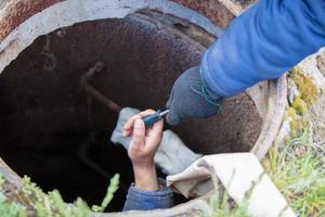 Sewer works. Industrial sewage treatment. Give a screwdriver for the worker in the sewer manhole. photo