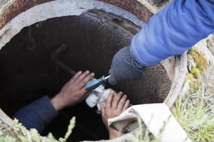 Sewer works. Industrial sewage treatment. Give a screwdriver for the worker in the sewer manhole. photo