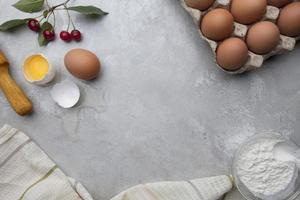 Ingredients baking flour eggs rolling pin berries kitchen textiles on gray background. Cookie pie or cake recipe mockup. Background preparation for culinary baking. photo