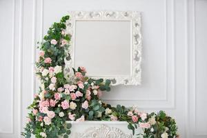 Mirror on a white wall, decorated with flower garlands. photo