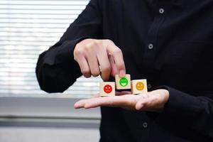 Businessman holding a wooden block cube with satisfaction icon symbol. Emotion, mindset and satisfaction concept. photo