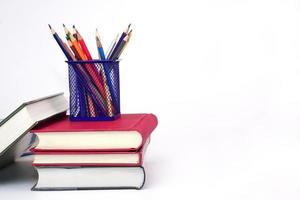 Crayon or colored pencils in box laying on a stack of books, white background. Knowledge and education concept. photo