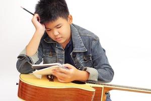 niño o adolescente pensando con tener un lápiz, cuaderno para tomando notas y acústico guitarra. aprendiendo, práctica y relajarse concepto. foto