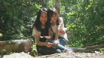 Asian mum and girl cheerful with many swarms of butterflies flying, beautiful wings, eating food on salt marshes in tropical forests of National Parks, outdoor learning experience, nature knowledge. video