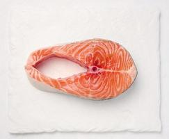 Raw piece of salmon on a white board, top view photo