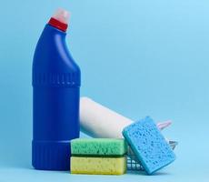 esponjas para el cocina y un azul botella con detergente en un azul antecedentes foto