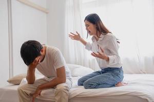 Internal violence. family conflict A woman is violently reprimanding her husband in an angry mood. make the husband feel bad In the bed inside the house, family quarrel concept. photo