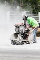 Worker cutting asphalt road photo