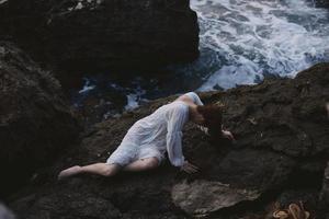 beautiful young woman lying on rocky coast with cracks on rocky surface unaltered photo