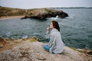 woman seated on the coast sweater landscape female relaxing photo