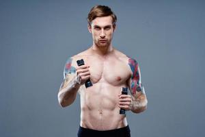 nude man doing sports on gray background and dumbbell tattoo cropped view photo