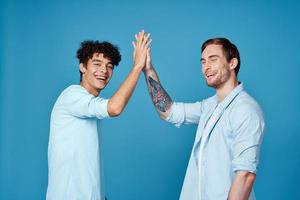 a man with a tattoo shakes hands with a curly guy on a blue background friends communication photo