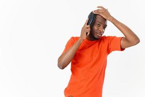 African American in orange t-shirt combing hair isolated background photo