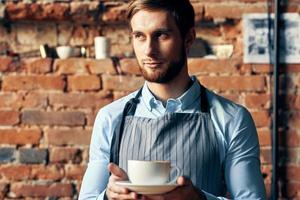 man in apron barista work professional a cup of coffee in hand photo