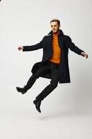 happy man in a coat jumped up on a light background and fashionable clothes trend of the season photo