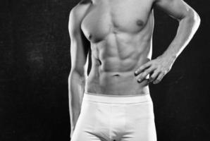 athletic men in white shorts pumped up press posing fitness dark background photo