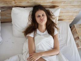 sad upset woman lying on bed top view photo