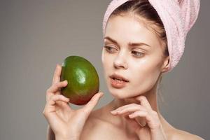 Pretty woman holding a mango in her hand a pink towel on her head close-up photo