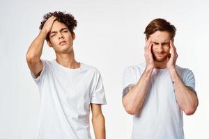 two men in white t-shirts holding their heads emotions discontent photo