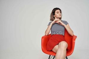 beautiful woman with glasses sitting on the red chair posing Studio photo