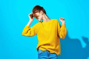 woman in yellow sweater holding hair blue background fashion photo