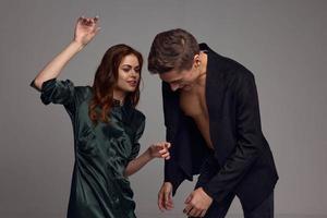 A man in a jacket on a naked torso and a woman with a raised hand photo