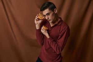 Nice man in a red shirt with oranges on a fabric background attractive style photo
